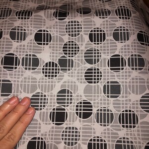 May include: White fabric with a repeating pattern of black and gray circles with a grid pattern inside. The circles are overlapping.