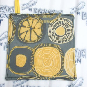 May include: A gray and yellow fabric pot holder with a geometric pattern of circles and lemons. The pot holder is handmade.
