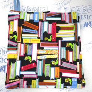 May include: A black fabric pot holder with a colorful book and worm design. The pot holder features various book titles like "English", "Biology", and "History". It has a blue hanging loop and is made of fabric.