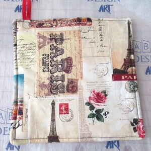 May include: A beige fabric pot holder with a patchwork design featuring images of the Eiffel Tower, Parisian postcards, and the words "Paris France".