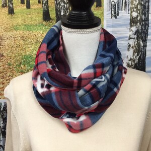 May include: A red, white, and blue plaid fleece infinity scarf. The scarf is folded in half and draped over a mannequin's neck.