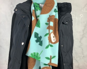 May include: A blue fleece scarf with a pattern of brown sloths hanging from branches and green leaves.