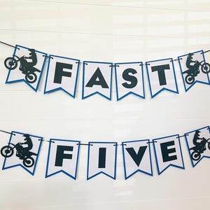 May include: A blue and white banner with the words "FAST FIVE" and a silhouette of a person riding a dirt bike on each end.