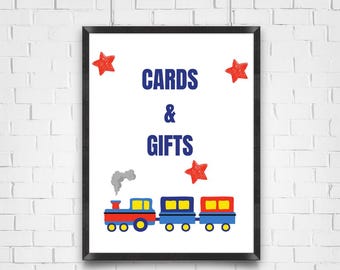 Puede incluir: Un cartel blanco con texto azul que dice "CARDS & GIFTS". El cartel está enmarcado en negro y presenta un tren rojo con detalles azules y blancos. Hay estrellas rojas en las esquinas superiores del cartel.