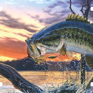 May include: A largemouth bass leaps out of the water, mouth open, with a lure in its mouth. The fish is in front of a sunset sky with clouds and trees in the background.