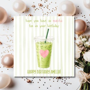 May include: A square greeting card featuring a light green striped background and a central illustration of an iced matcha drink in a clear plastic cup with a green straw and a pink heart. Text reads: hope you have so matcha fun on your birthday HAPPY BIRTHDAY AMELIA!