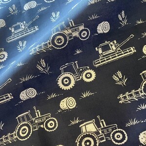 May include: Navy blue fabric featuring a repeating pattern of white tractors, hay bales, and wheat. The design has a rustic, farm theme, suitable for craft projects or home decor.