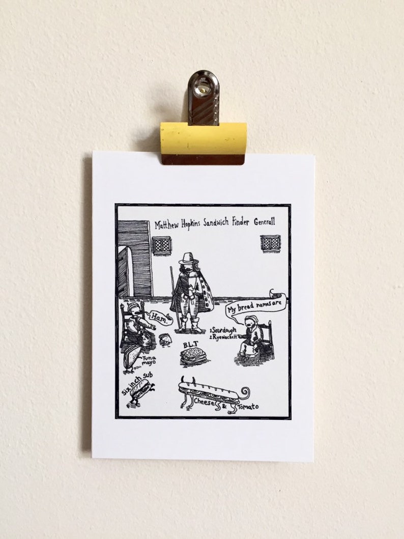 May include: A black and white cartoon print of a historical figure, Matthew Hopkins, with sandwich options. The print includes text bubbles with sandwich ingredients and names, such as "Ham" and "BLT". The print is held by a yellow clip.
