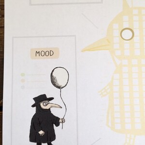 Op de afbeelding: Illustratie van een zwartgeklede pestdokter met een witte ballon. De afbeelding maakt deel uit van een groter kunstwerk met het woord "MOOD" boven de dokter. De dokter draagt een zwarte hoed en een lang snavelmasker. Het kunstwerk heeft een ietwat duister thema.