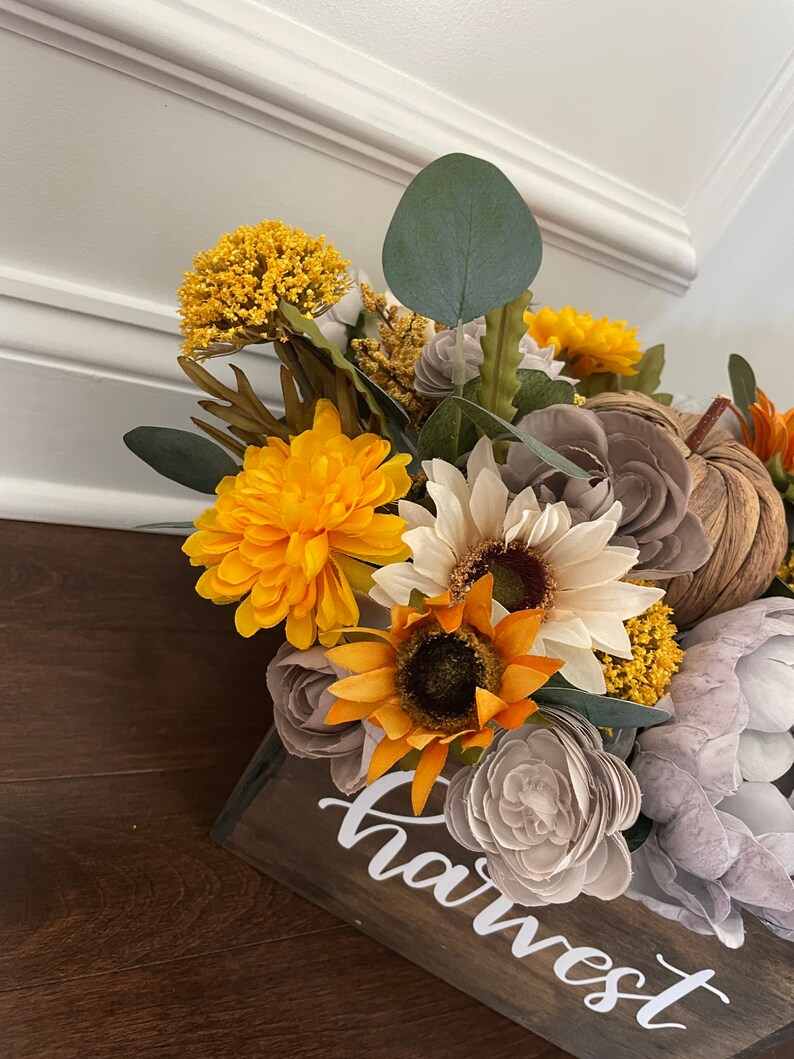Peut inclure: Une bo&icirc;te en bois avec le mot "harvest" &eacute;crit dessus. La bo&icirc;te est remplie d'une vari&eacute;t&eacute; de fleurs d'automne, dont des tournesols, des chrysanth&egrave;mes et de l'eucalyptus.