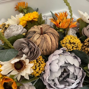 Peut inclure: Un arrangement floral sur le th&egrave;me de l'automne avec des tournesols, des pivoines grises et une citrouille tiss&eacute;e. L'arrangement est dans un panier en bois.
