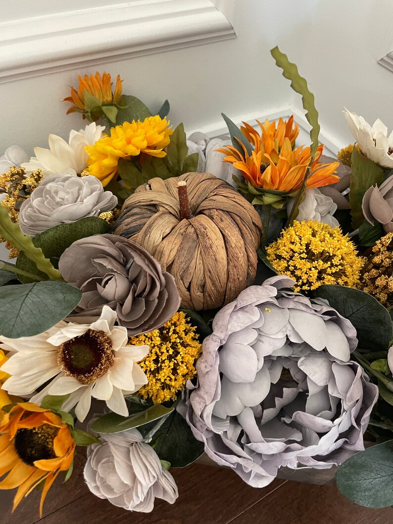 Peut inclure: Un arrangement floral sur le th&egrave;me de l'automne avec des tournesols, des pivoines grises et une citrouille tiss&eacute;e. L'arrangement est dans un panier en bois.