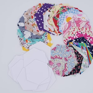 May include: A set of fabric hexagons in various colours and patterns, including floral, geometric, and animal prints. The hexagons are arranged in a circle, with a set of white paper hexagons in the centre.