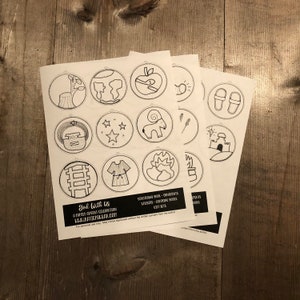 May include: A set of printable Christmas ornament circles featuring black and white illustrations of various religious symbols, including a star, a ram, a ladder, a burning bush, and a manger. The text "God With Us" and "A Family Advent Celebration" is printed at the bottom of the page.