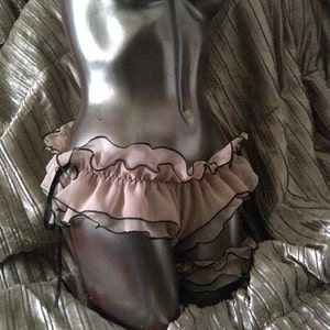 May include: A black and pink ruffled lingerie set with a delicate lace trim.