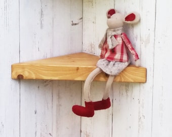 May include: Three wooden corner shelves in a natural wood finish. The shelves are mounted on a white wall. A small stuffed mouse toy is sitting on the middle shelf.