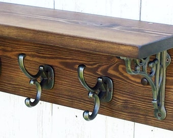 May include: A wooden shelf with three metal hooks and decorative metal brackets. The shelf is stained a dark brown color and the hooks and brackets are a silver color.