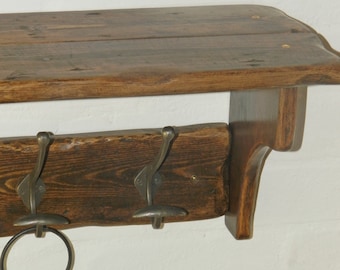 Könnte beinhalten: Ein rustikales Holzregal mit drei Metallhaken, perfekt zum Aufhängen von Mänteln, Hüten oder Taschen. Das Regal hat eine dunkelbraune Beize und eine natürliche Holzoptik. Die Haken sind aus Metall und haben eine gebürstete Oberfläche.