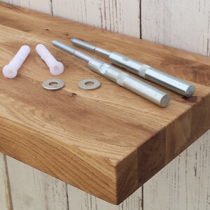 May include: A wooden shelf with a natural finish, two white plastic anchors, two silver metal screws, and two silver metal washers.