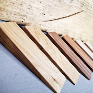 May include: A set of six wooden wedges in various shades of brown, arranged in a staggered pattern. The wedges are made of different types of wood, with varying grain patterns and textures.