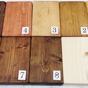 May include: Nine wood samples stained in different shades of brown, yellow, and orange. The samples are numbered 1 through 9.