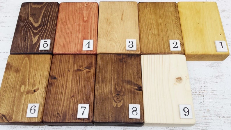 May include: Nine wood samples stained in different shades of brown, yellow, and orange. The samples are numbered 1 through 9.