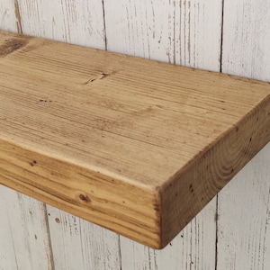 May include: A rustic wooden shelf with a natural wood finish. The shelf is made of reclaimed wood and has a rough, textured surface. It is perfect for adding a touch of farmhouse style to any room.