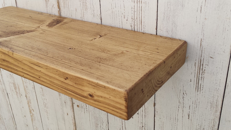 May include: A rustic wooden shelf with a natural wood finish. The shelf is made of reclaimed wood and has a rough, textured surface. It is perfect for adding a touch of farmhouse style to any room.
