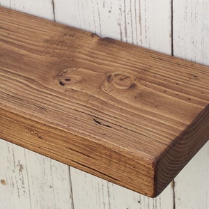 May include: A rustic wooden shelf with a dark brown stain. The shelf is made of reclaimed wood and has a natural, distressed look.