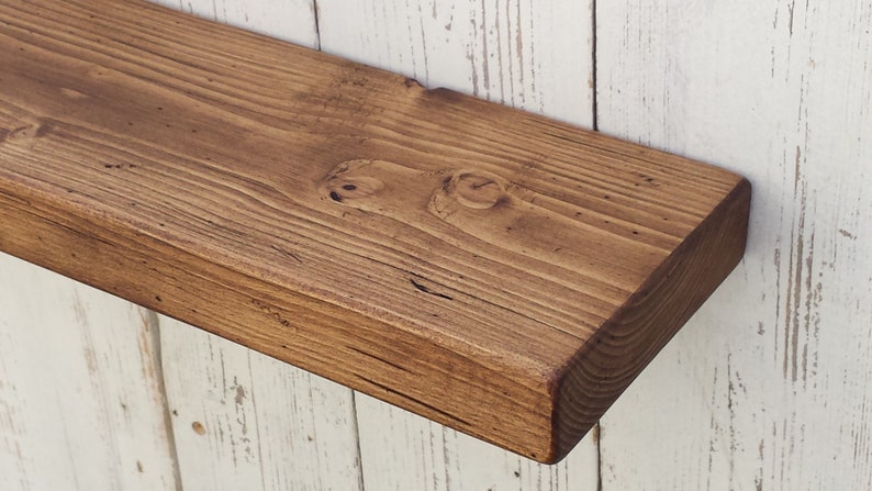May include: A rustic wooden shelf with a dark brown stain. The shelf is made of reclaimed wood and has a natural, distressed look.