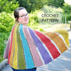 May include: A rainbow crochet shawl with a white crocheted border. The shawl is made with a variety of colorful yarns and has a lacy pattern.