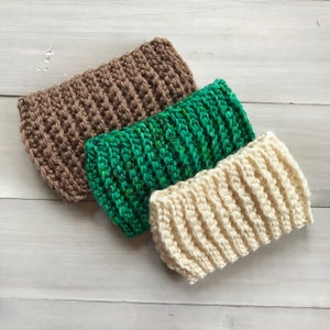 Puede incluir: Tres diademas de crochet en colores marr&oacute;n, verde y crema. Las diademas est&aacute;n apiladas una encima de la otra.