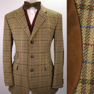 May include: A tan and brown plaid blazer featuring a three-button front closure, two flap pockets, and brown suede elbow patches. The blazer is worn over a white collared shirt, a dark red vest, and a textured brown bow tie on a mannequin.
