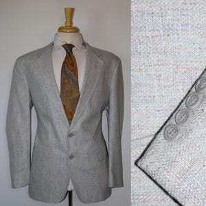 May include: A gray blazer with a subtle pattern. The blazer has a single button closure and a notched lapel. The blazer is made of a lightweight fabric and has a relaxed fit.