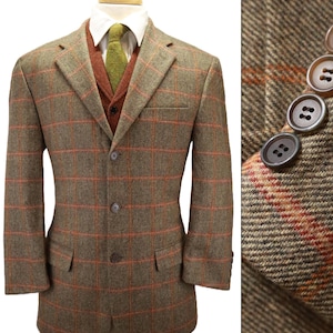 May include: A brown and olive green tweed blazer with an orange windowpane check pattern, featuring a three-button front closure, notched lapels, and two flap pockets. The sleeve cuffs are detailed with four stacked brown buttons.