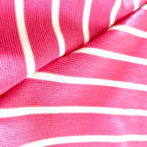 May include: Pink and white striped fabric with a textured surface.