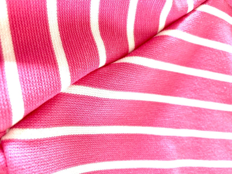 May include: Pink and white striped fabric with a textured surface.