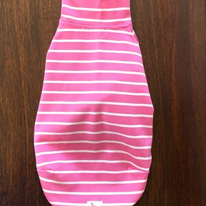 May include: Pink and white striped dog sweater with a small white tag that says "IG Blue".