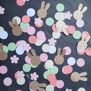 May include: Assortment of confetti featuring pastel pink, green, and cream colored circles, and gold glitter bunny shapes.