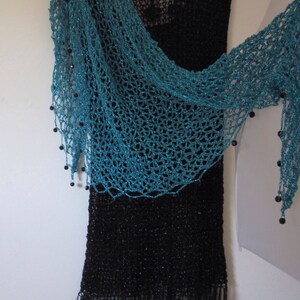Turquoise shawl arranged side-swept on a black dress, highlighting the beaded edge and airy crochet.