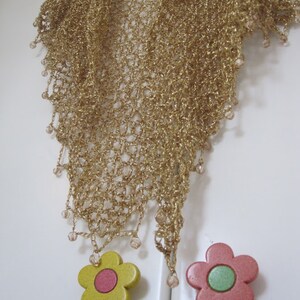 Champagne gold shawl on a white door with flower-shaped knobs, full view of the sparkling wrap.