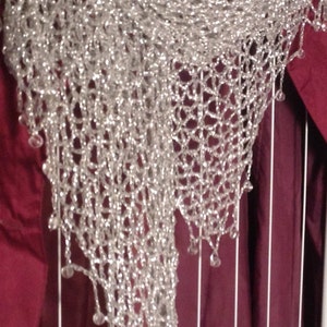 Close-up of the silver lurex shawl over a burgundy garment, showing the beaded edge and openwork crochet.