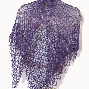 Eggplant purple lurex shawl hanging in a soft drape, side view with red flowers arranged below.