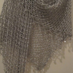 Close-up of the silver lurex shawl texture, showing dense hand stitches, fine beads, and metallic sheen along the hem.