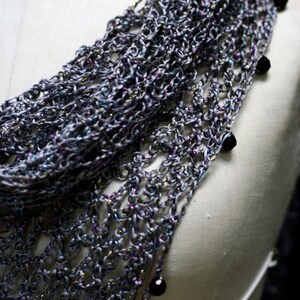 Close-up of the grey shawl's beaded edge on the mannequin, dark beads hanging from the scalloped trim.