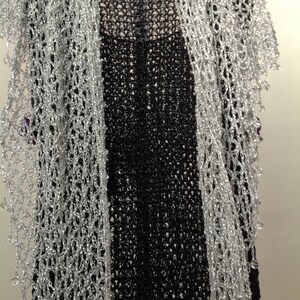 Silver beaded lurex shawl arranged over a black dress, front view of the openwork wrap and beaded edging.