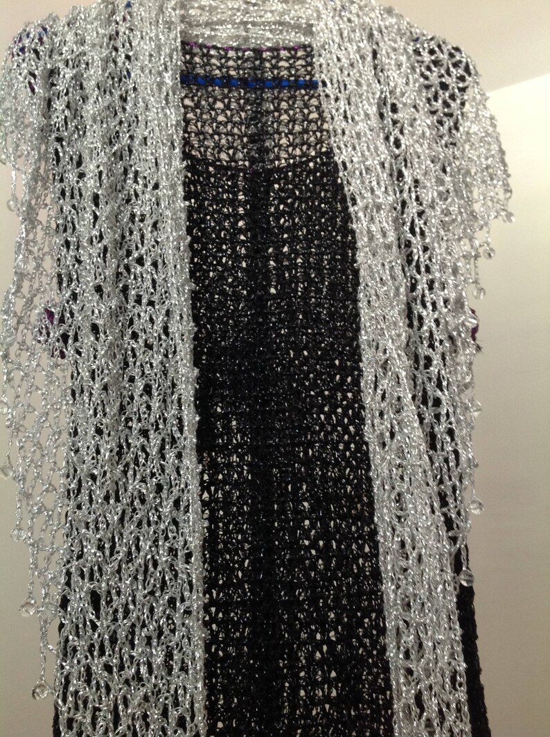 Silver beaded lurex shawl arranged over a black dress, front view of the openwork wrap and beaded edging.