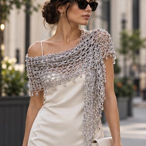 Woman in a white dress with the silver lurex shawl draped over one shoulder, photographed on an outdoor terrace.
