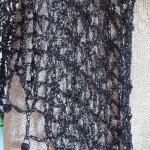 Close-up of the black lurex crochet, revealing tight stitches and dark beads hanging from the edge.