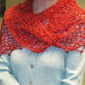 Red shawl worn as a shoulder wrap over a light blue top, photographed in an indoor lobby setting.